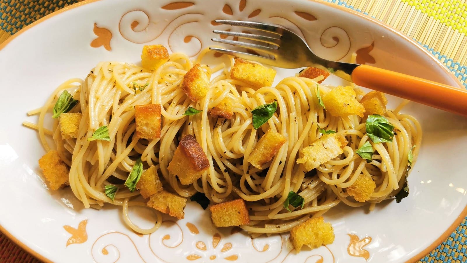 Anchovy pasta on a plate garnished with basil.