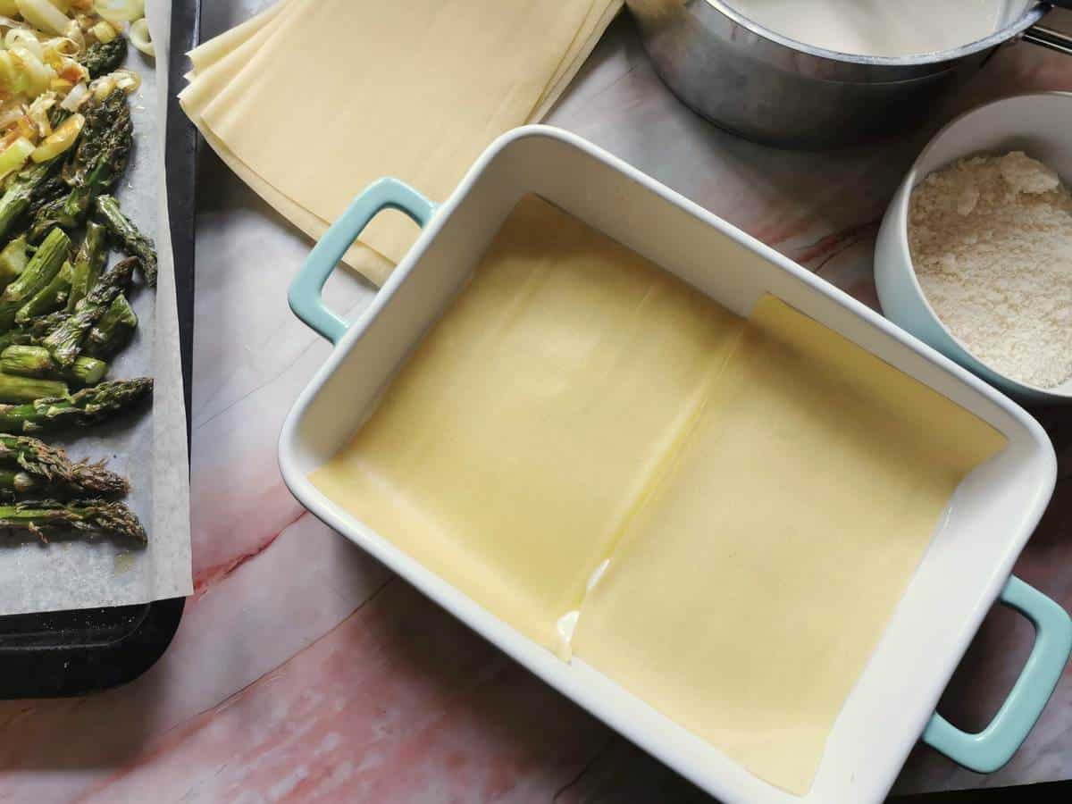 Two sheets of lasagne placed on top of bèchamel in oven dish.