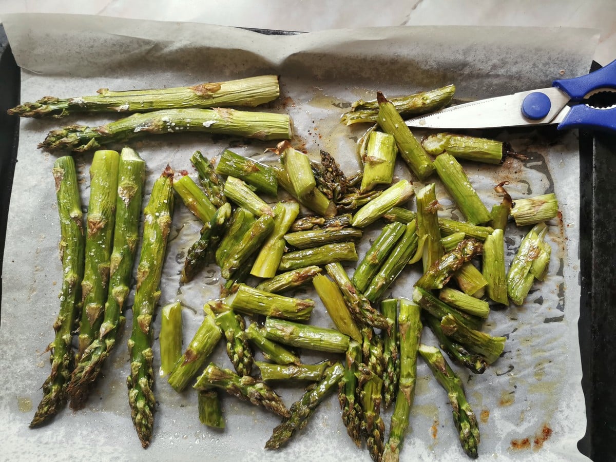 Roasted asparagus on oven tray cut into pieces.