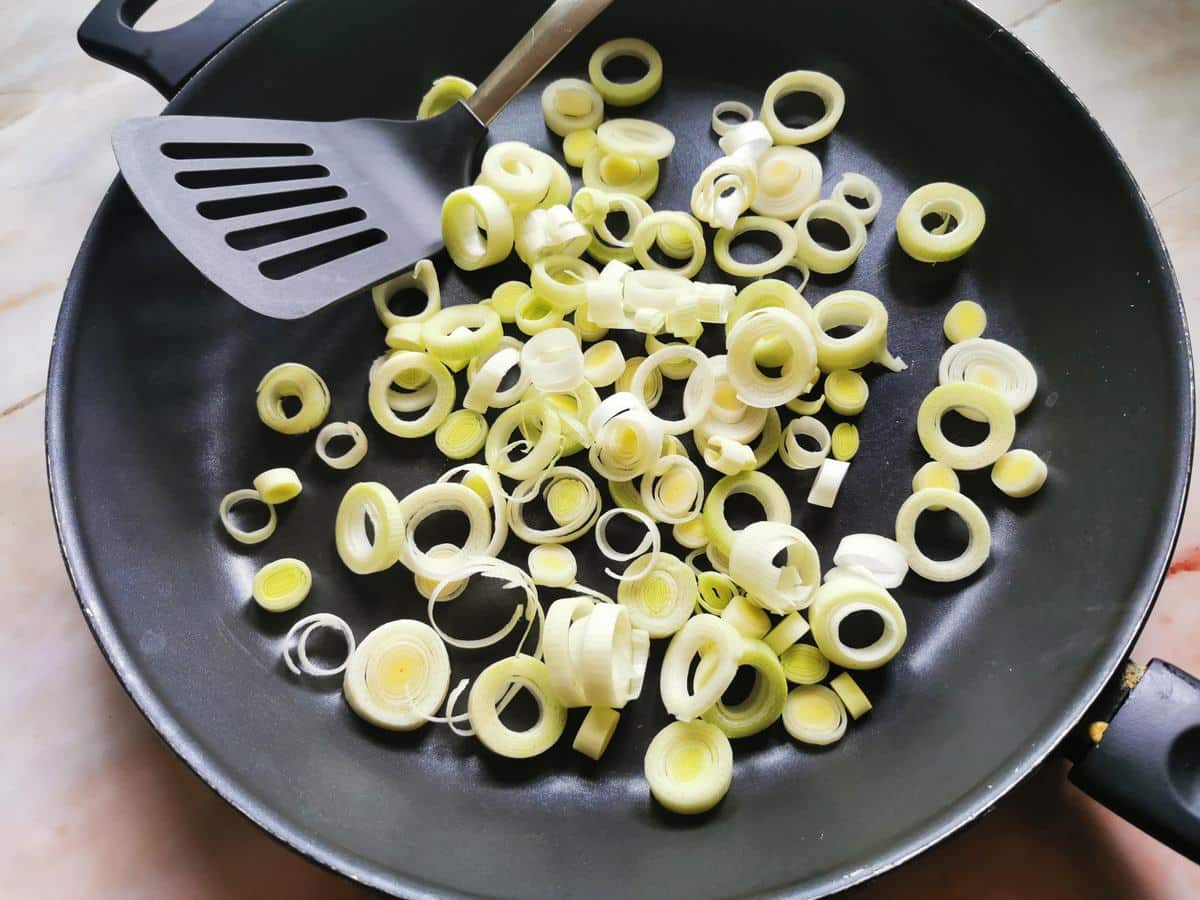 Thin slices of leeks in frying pan.