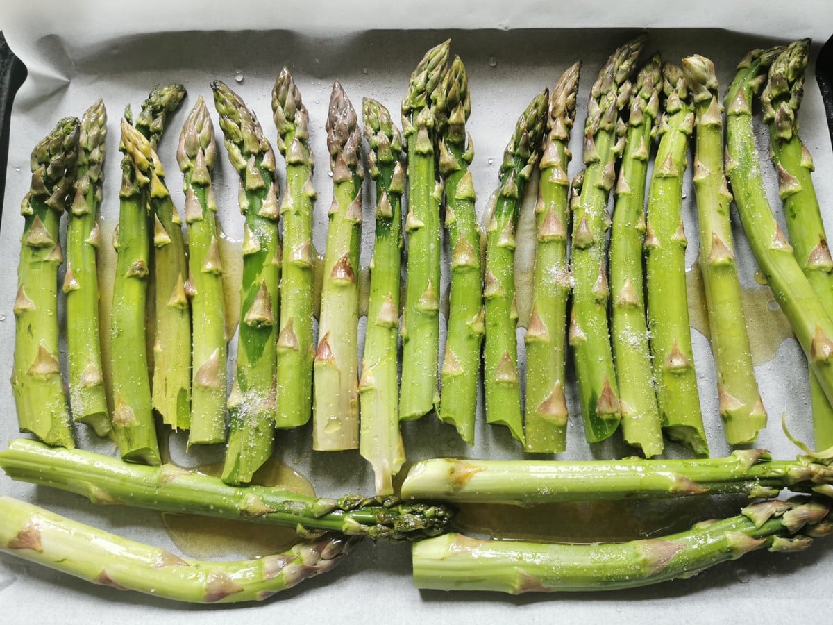 Asparagus spears on oven tray lined with baking paper.