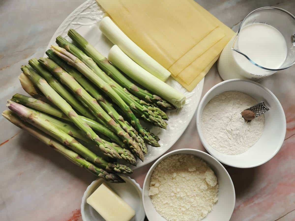Ingredients for aparagus lasagna (lasagne agli asparagi) on marble work top.