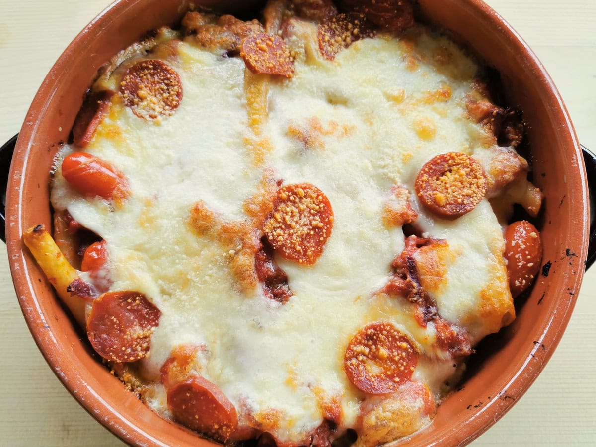 Spicy sausage and ziti pasta in a baking dish.