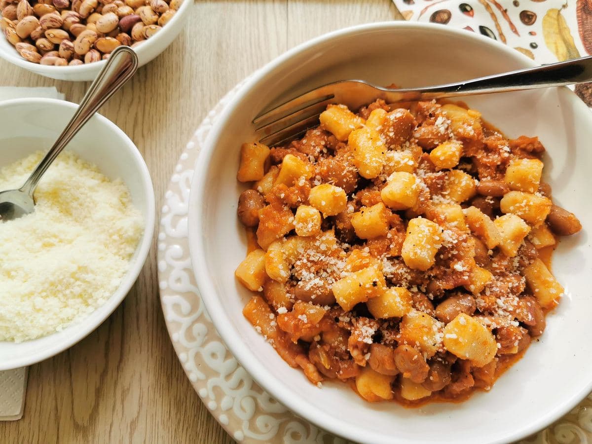 Bread gnocchi with a sausage sauce in a bowl with pecorino