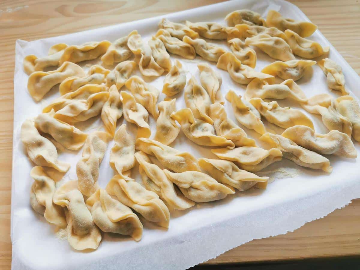 Ready homemade casoncelli on flour dusted baking paper.