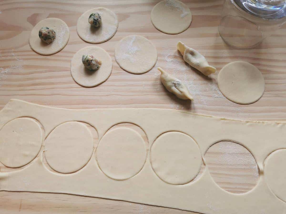 Circles of casoncelli pasta dough, some with balls of filling in the middle.