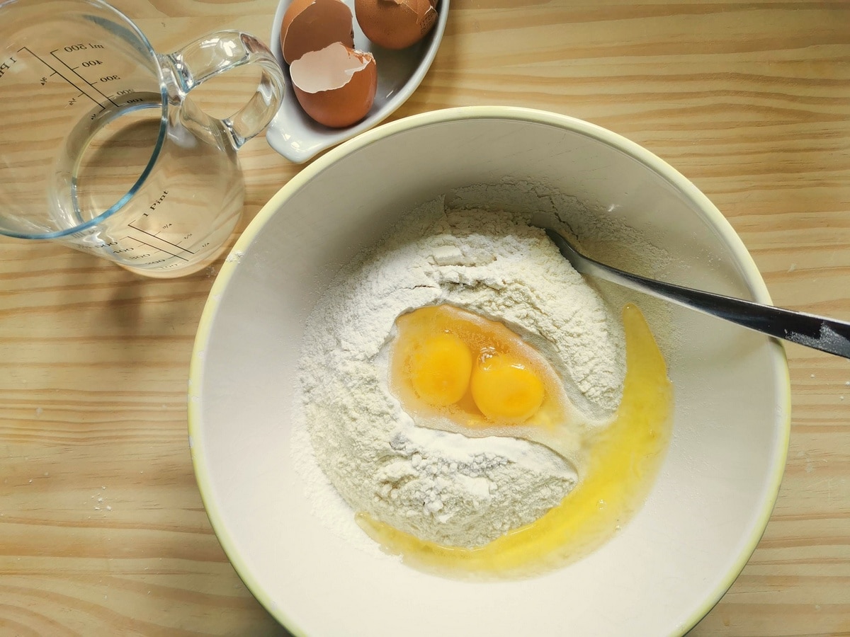 Flour and eggs in white bowl.