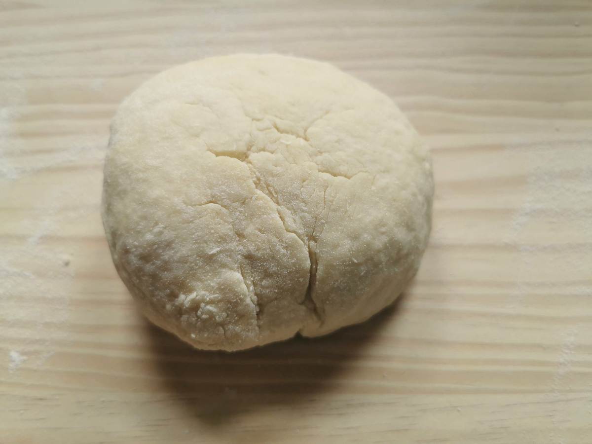 Ball of ready casoncelli dough on wood work surface.