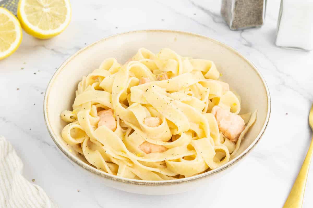 Creamy lemon salmon pasta in white bowl.