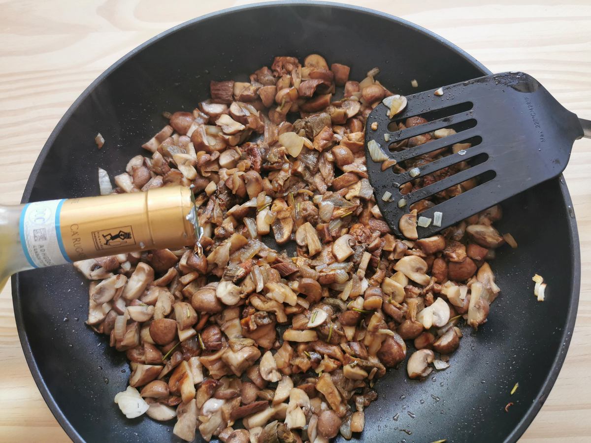 Mushrooms cooking in a pan with white wine.