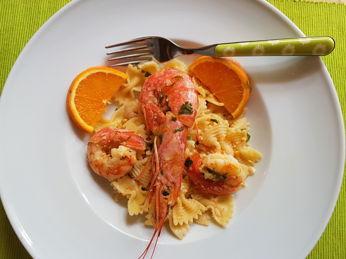 Farfalle pasta with prawns and orange in a bowl.