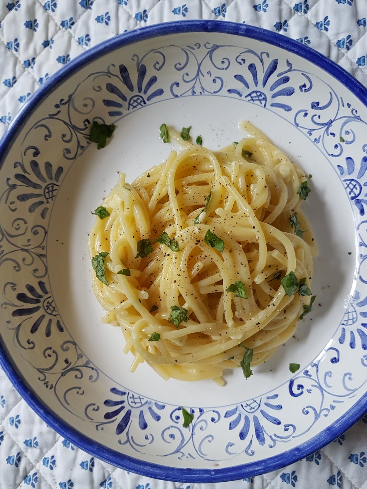 Lemon water spaghetti in a bowl on a kitchen table.