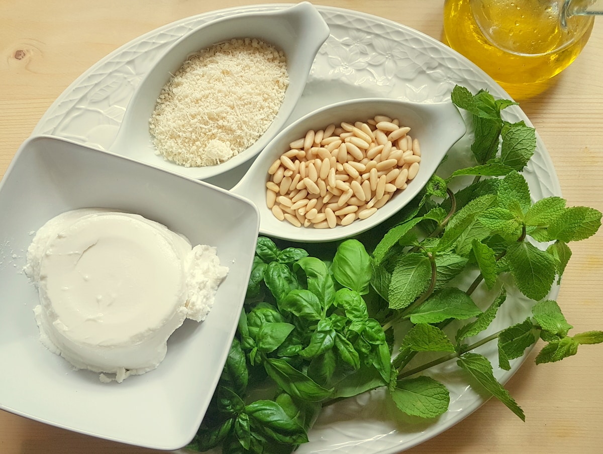 Mint leaves, basil leaves, pine nuts, Parmigiano Reggiano, ricotta and extra virgin olive oil on a kitchen table. 