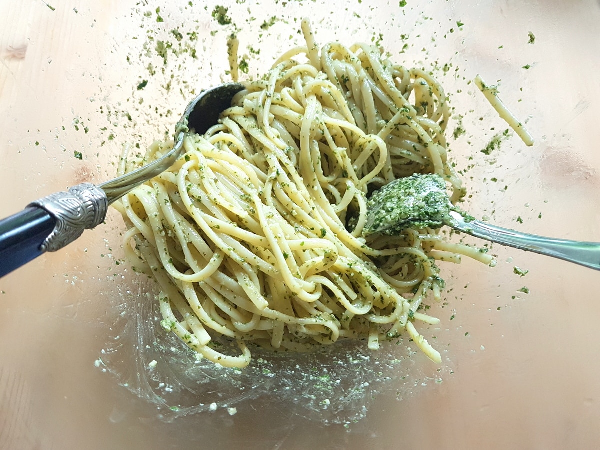 Mint pesto mixed with pasta in a bowl.
