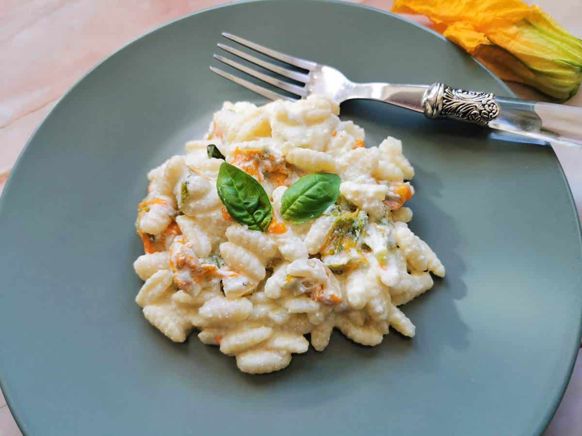 Malloreddus pasta with zucchini flowers, ricotta and saffron on a plate.