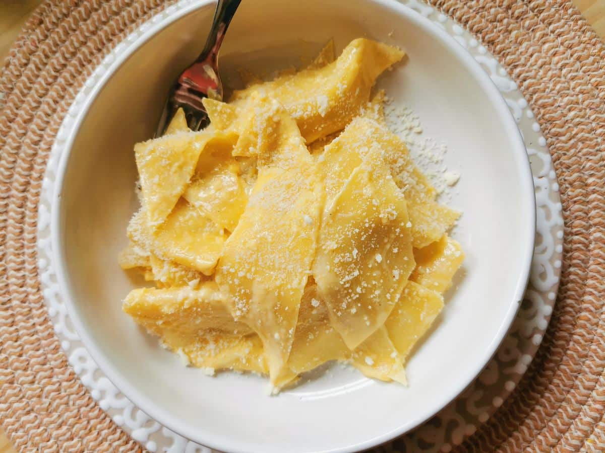 Maltagliati pasta with mascarpone in white bowl.