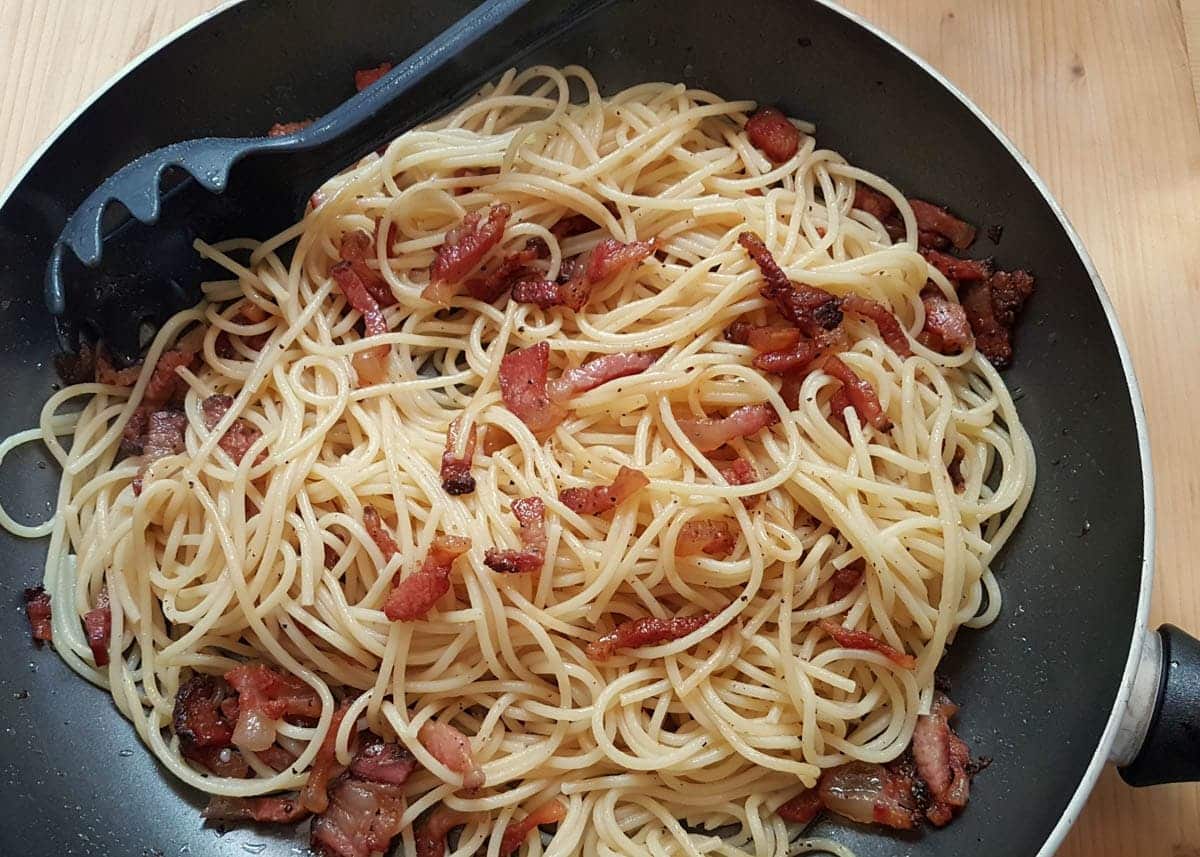 Spaghetti and guanciale that has been mixed together.