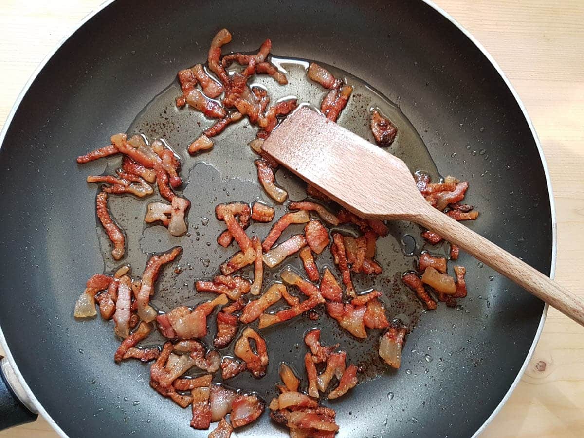 Cooked guanciale slices in frying pan.