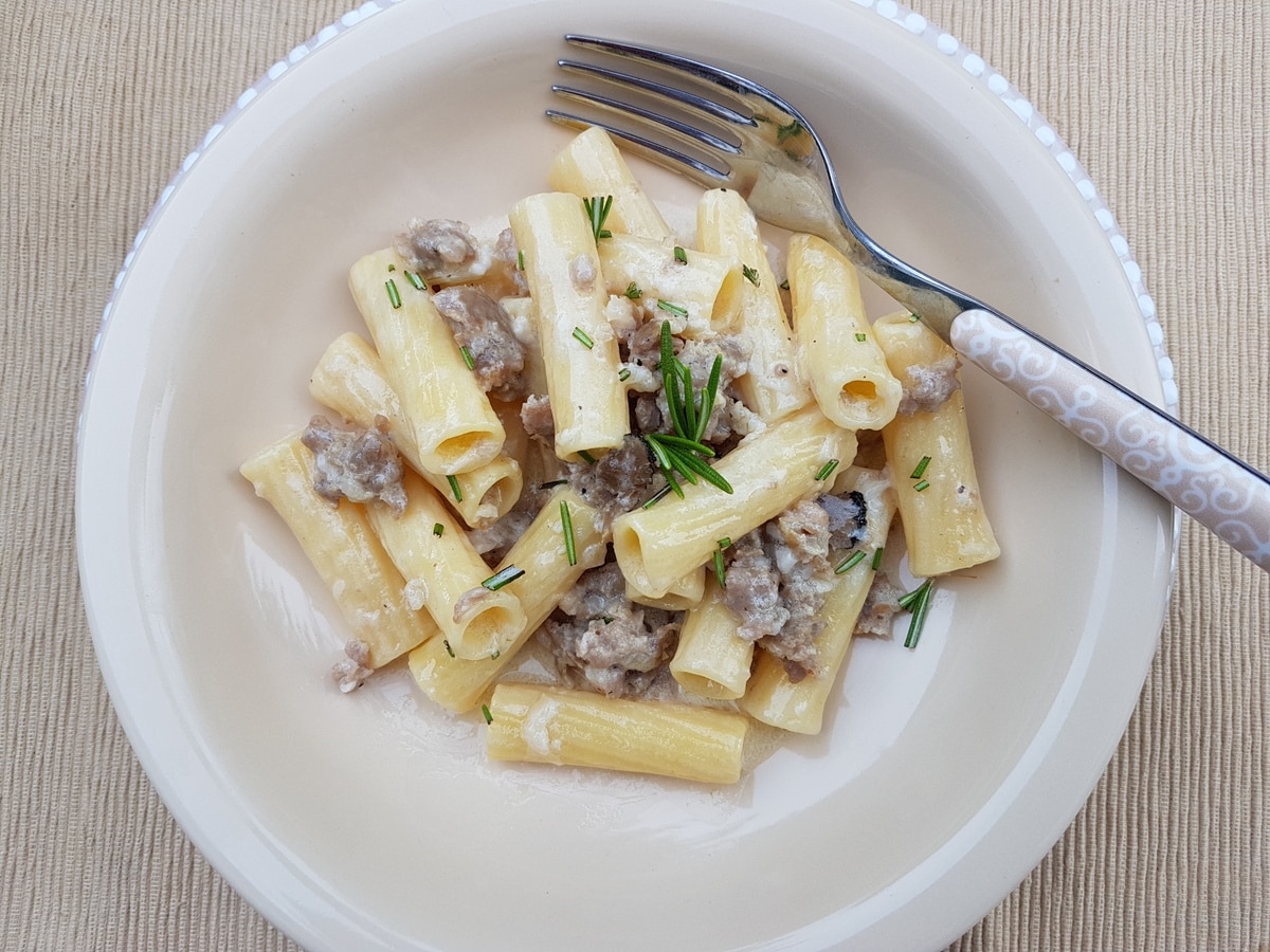 Pasta alla norcina in a white bowl with a fork.