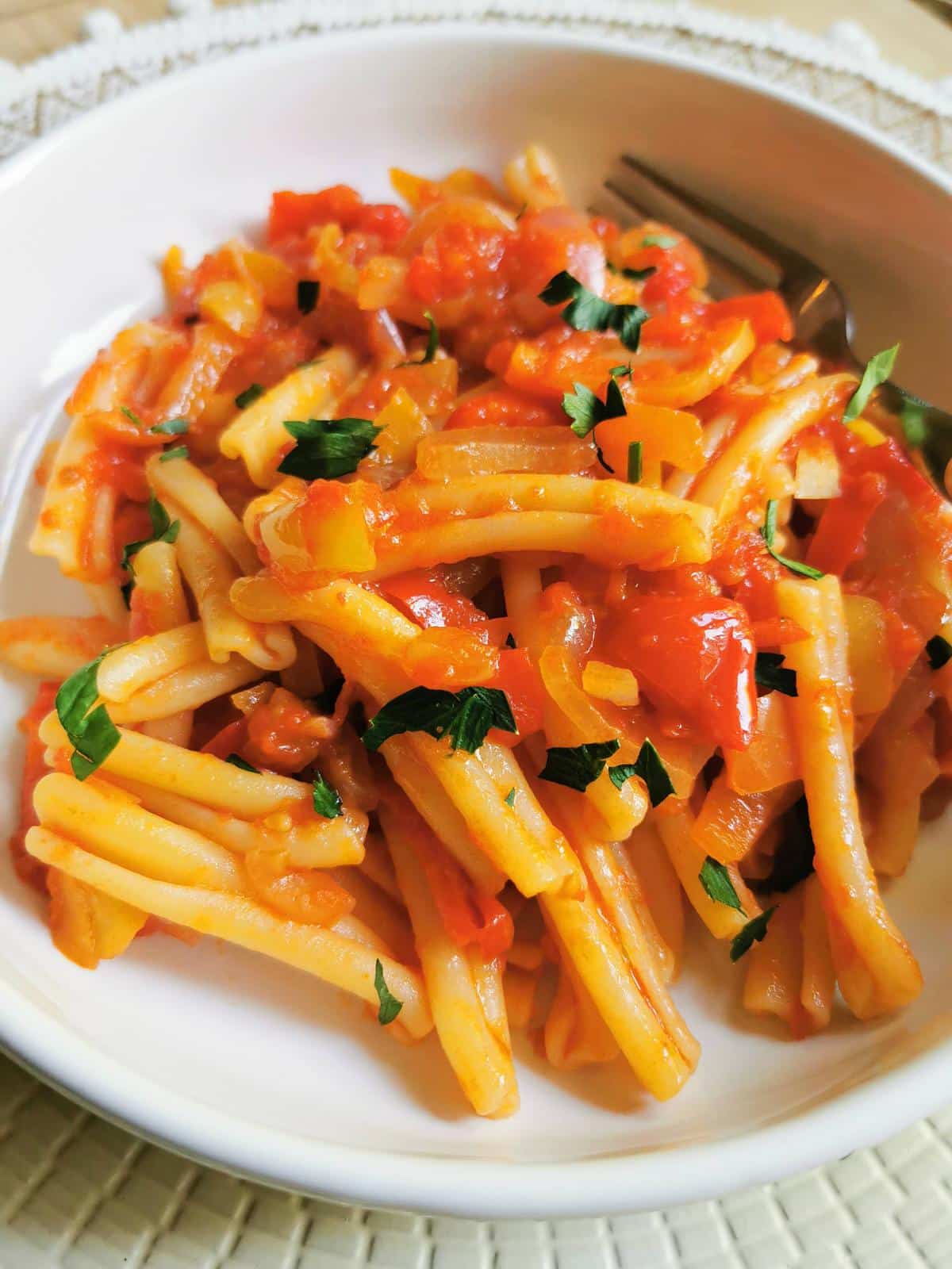 Pasta with a sweet pepper sauce in a bowl garnished with parsley.
