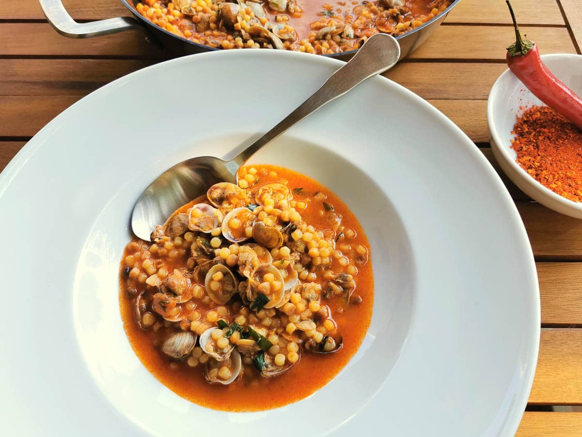 Fregola with clams in a bowl. Sardinian seafood pasta recipe.