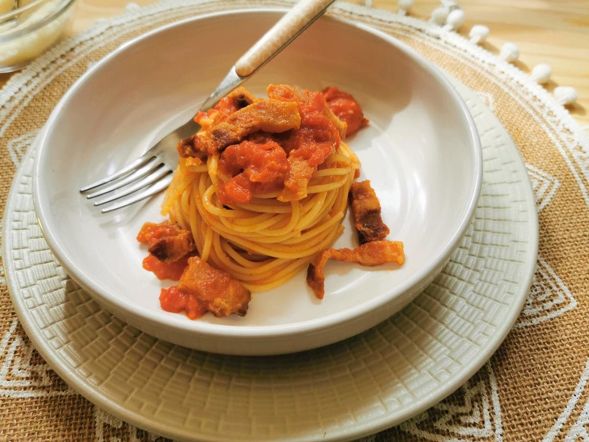 Pasta all’Amatriciana in a white bowl with a fork.