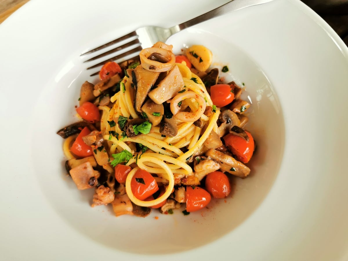 Spaghetti mare e monti garnished with sliced parsley.