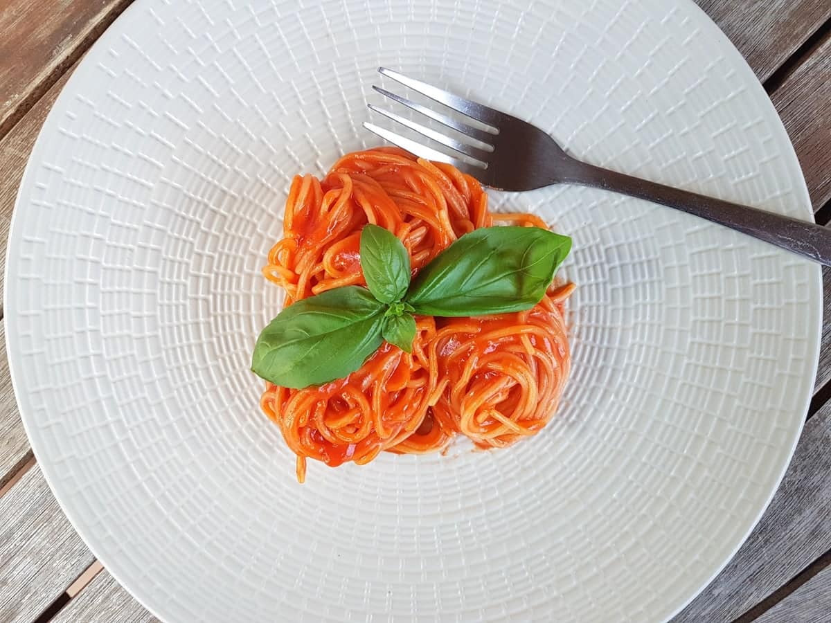 Spaghetti with tomato sauce garnished with basil.